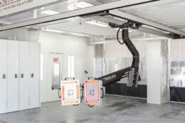 A large crane is in a Prep Environments garage with white cabinets.